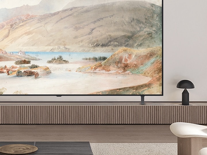 Nahaufnahme einer Ecke eines LG OLED-Fernsehers in einem Wohnzimmer. Er steht auf einem Standfuss und man kann sehen, wie gut die schlanke Silhouette mit der Inneneinrichtung harmoniert.