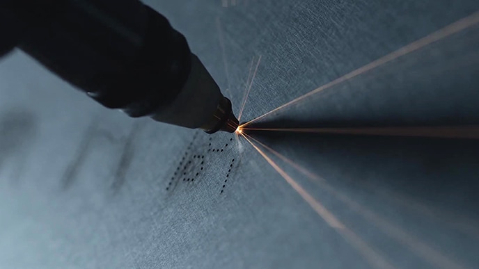 Das Symbol für die Benutzeroberfläche des LG SIGNATURE Refrigerator wird von einem Werkzeug in den Edelstahlkörper geschnitzt.