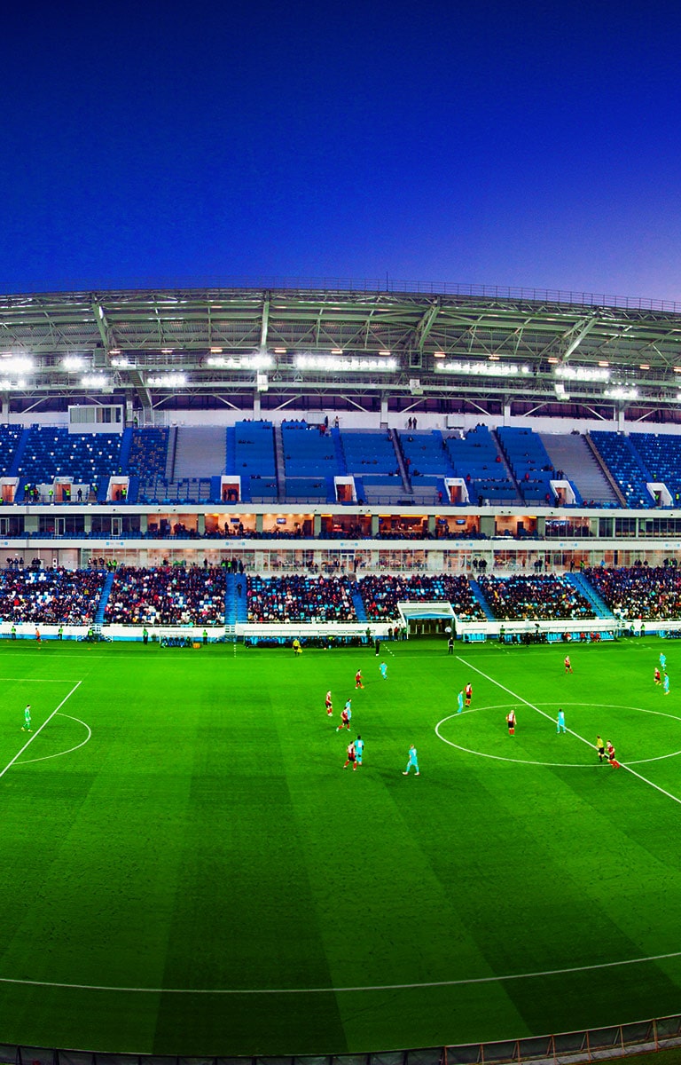 Ein weiter Blick auf ein Fussballstadion mit Menschenmenge und einem gerade laufenden Spiel.