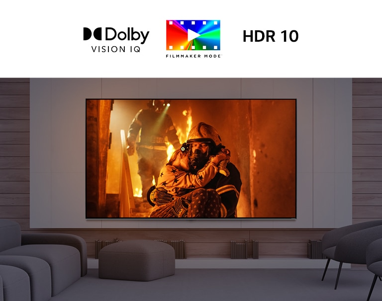 Großbildfernseher, der vor mehreren niedrigen Stühlen an der Wand montiert ist. Der Bildschirm zeigt einen Mann, der ein Kind aus einem brennenden Gebäude trägt.