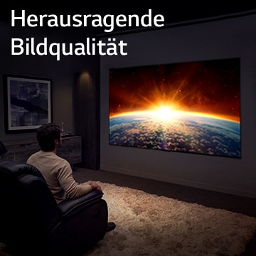 Ein Mann sitzt auf einem Sofa in einem dunklen Raum und sieht im Fernsehen, wie die Sonne hinter der Erde aufgeht.