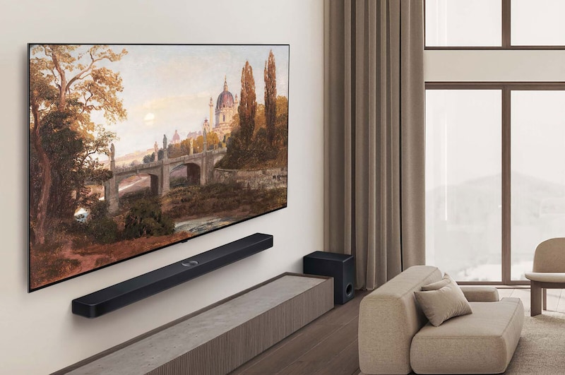 Gesamtansicht eines hochwertigen Wohnzimmers in gedeckten Erdtönen. An der Wand hängt ein LG OLED AI B5 4K Smart TV mit einem Kunstwerk auf dem Bildschirm. Darunter ist eine LG Soundbar montiert.