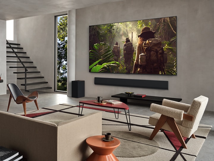 Weite Ansicht eines Wohnzimmers in einem hochwertigen Haus. Ein Paar sieht sich einen Film auf seinem an der Wand montierten LG OLED-Fernseher an. Das Design des Fernsehers fügt sich elegant in die Wand und die Inneneinrichtung ein.