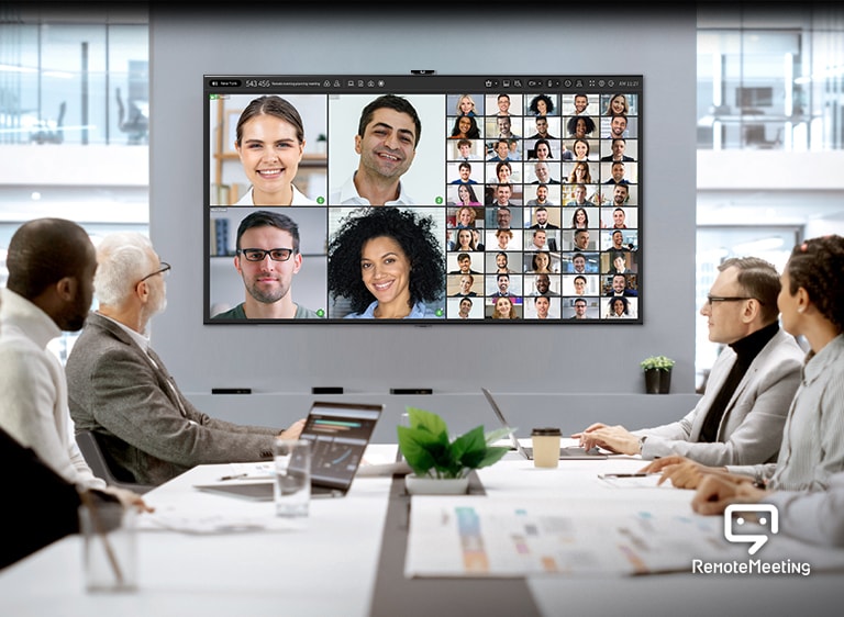 Die Teilnehmer sind in einem Konferenzraum versammelt und führen eine Videokonferenz über die Remote Meeting App auf dem Fernseher durch.