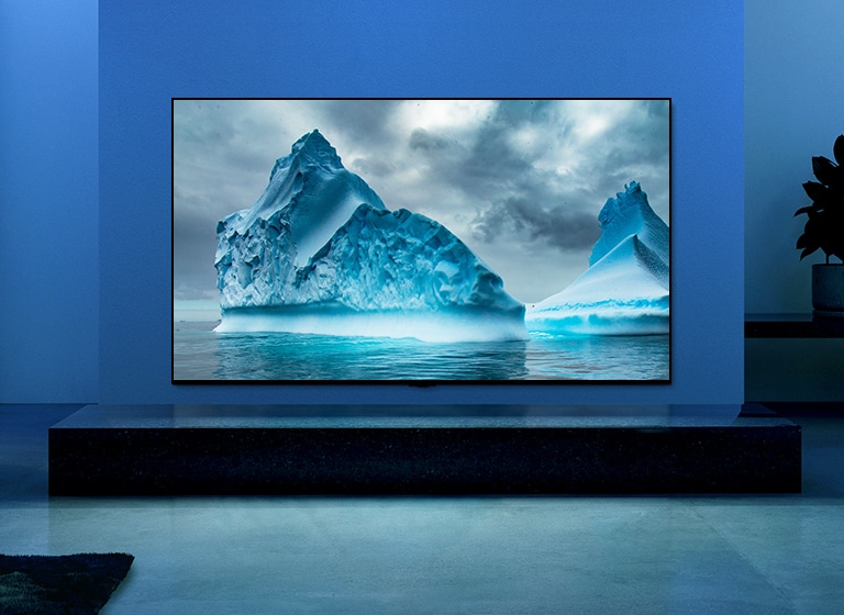 La vidéo montre en gros plan l’image d’un iceberg, et sur cette image flotte un effet visuel de circuit bleu. La scène change pour montrer un téléviseur suspendu dans le salon avec un éclairage et un fond bleus. Un vaste iceberg s’affiche sur l’écran du téléviseur.