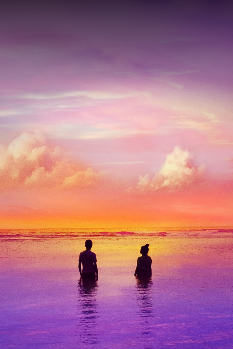 Deux personnes debout dans un océan – un océan légèrement violet. Lors d’un coucher de soleil.