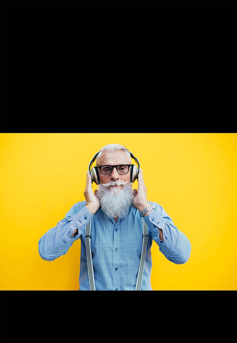 Un grand-père se tient devant un mur jaune – portant un casque.