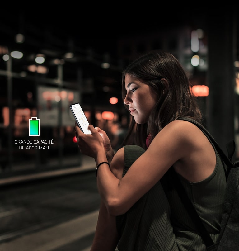 Une femme en train de surfer sur internet sur son smartphone tard le soir dans une station de métro avec suffisamment de batterie