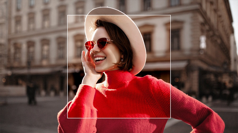 Image d'une femme dans une ville. Une incrustation carrée est appliquée sur la femme, représentant la super mise à l'échelle de l'IA, la mettant au point avec des détails sur une toile de fond artistiquement floue.