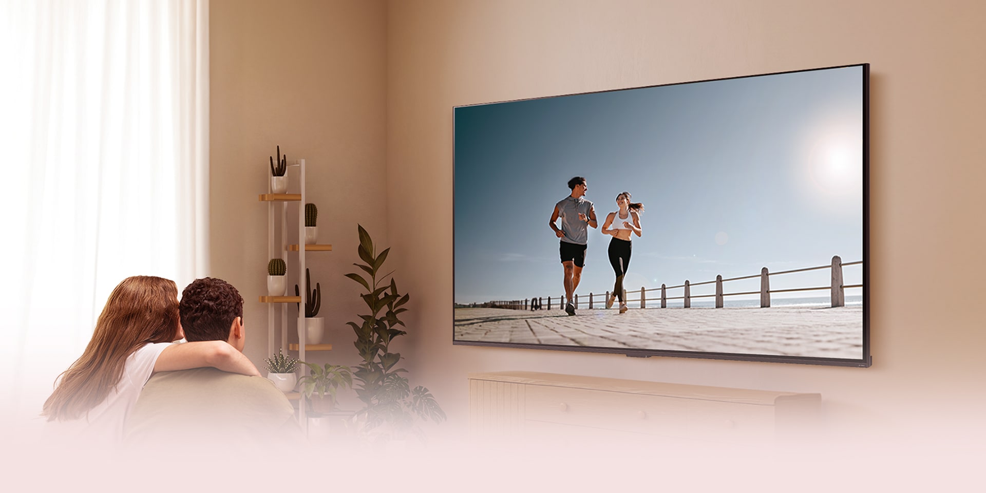 Pareja sentada en el sofá viendo una TV LG con una escena de dos personas corriendo junto al mar.