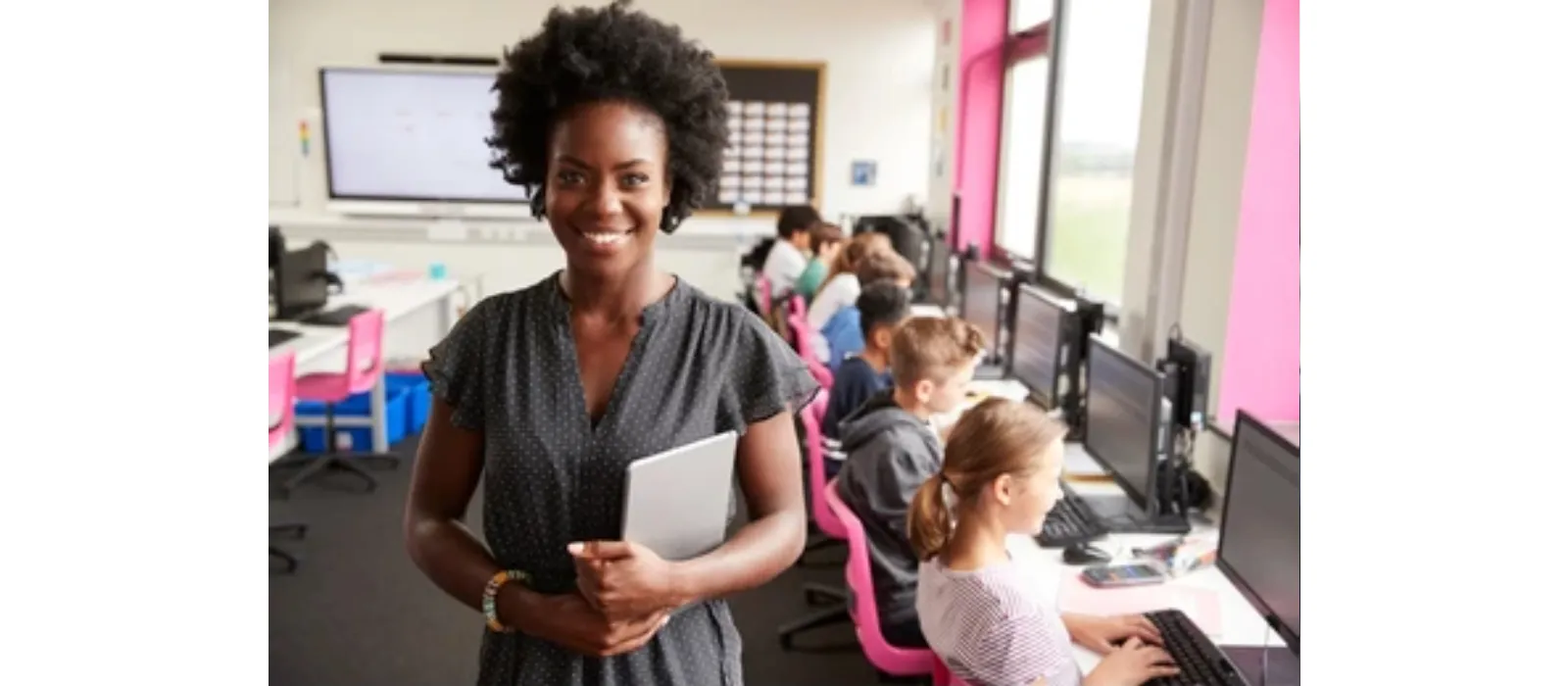 Mujer en un salon de clases con mas personas en computadores sentadas