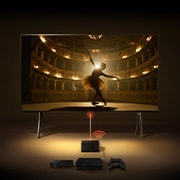 Una Zero Connect Box frente a un LG SIGNATURE OLED M4, y una señal Wi-Fi roja y un haz rojo emitiéndose hacia el televisor. El televisor muestra a una bailarina bailando sola en el escenario.