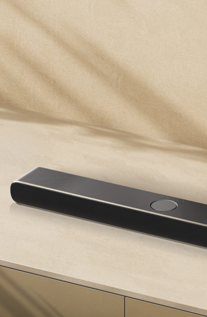 LG Soundbar na béžovém povrchu na béžovém pozadí v natočené letecké perspektivě.