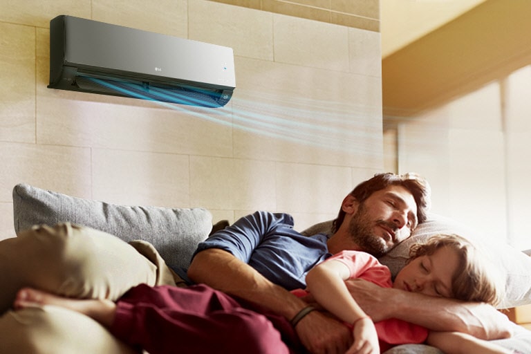 Na gauči pod klimatizací spí otec s dcerou. Klimatizace nad nimi vytváří chladivý vzduch.