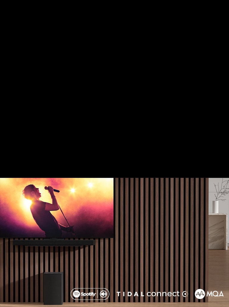 Televizor LG OLED C je umístěn na stěně, pod ním je připevněn soundbar LG SC9S pomocí exkluzivního držáku. Subwoofer se nachází pod ním. Televizor zobrazuje koncertní scénu.