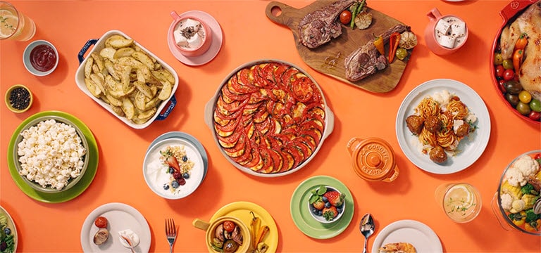 Zobrazuje různé pokrmy umístěné na stole připravené pomocí LG Neochef.