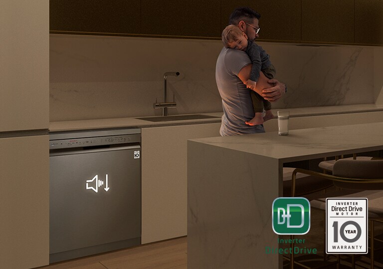 Muž, který držel spící dítě ve spoře osvětlené kuchyni, v pozadí tiše pracuje myčka.