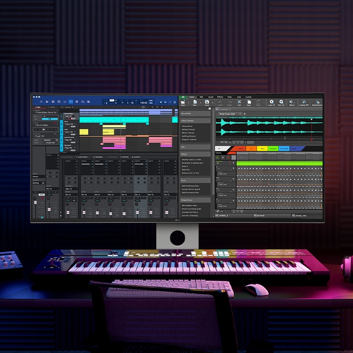 V tmavé místnosti s modrým a fialovým osvětlením stojí monitor UltraFine s nahrávacím programem. Na stole, na kterém stojí, je umístěna klávesnice, tablet, sluchátka a další příslušenství.