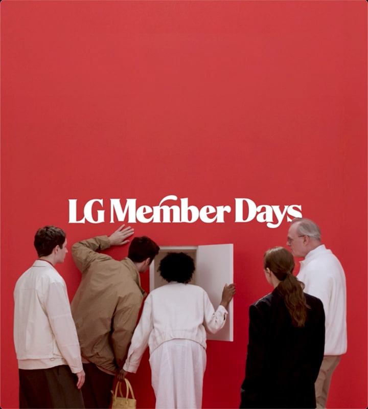 Mehrere Personen schauen auf eine kleine Tür in einer roten Wand und sind neugierig, was das Event LG Member Days ist.