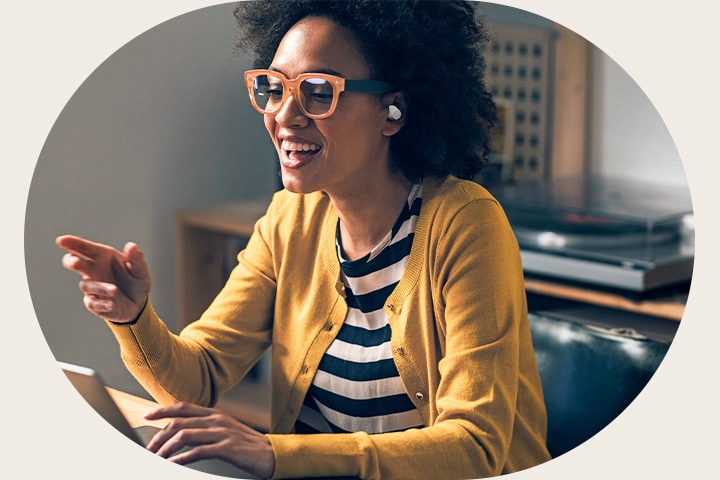 Eine Frau mit weißen Kopfhörern spricht mit ihren Fingern nach vorne und nutzt die Anruffunktion des Kopfhörers.