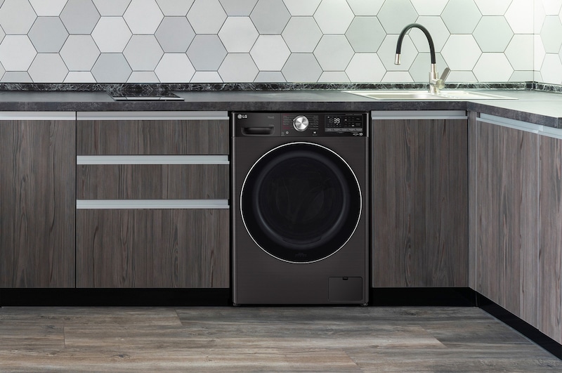 Der schwarze LG Waschtrockner V9WD128H2B (12kg Waschen/8kg Trocknen), sauber unter der Arbeitsplatte in einer modernen Küche installiert, mit Energieeffizienzklasse E.