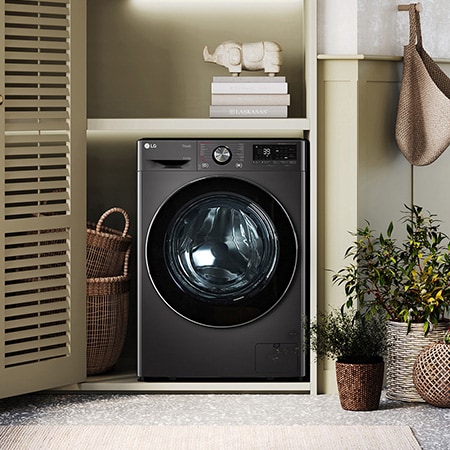 Der schwarze LG 9 kg Waschtrockner W4WR70E6YB, mit seinem platzsparenden 2-in-1-Design in einem stilvollen Wäscheschrank installiert, mit Energieeffizienzklasse D.