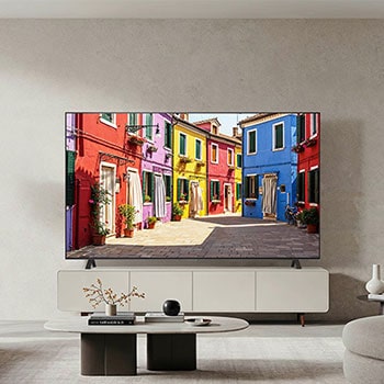 Lifestyle-Aufnahme des LG OLED AI B4 4K Smart TV auf seinem Standfuß in einem modernen Wohnzimmer, das eine bunte Straßenszene zeigt.