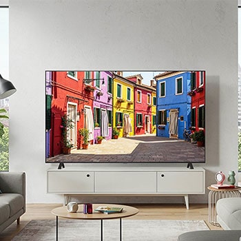 Lifestyle-Aufnahme des LG OLED AI B4 4K Smart TV auf seinem Standfuß in einem modernen Wohnzimmer, das eine bunte Straßenszene zeigt.