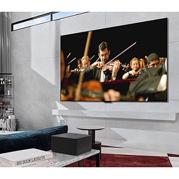 Zero Connect Box auf einem Tisch in einem luxuriösen Wohnzimmer streamt eine Orchesteraufführung auf den LG Signature OLED M4 True Wireless TV Fernseher.