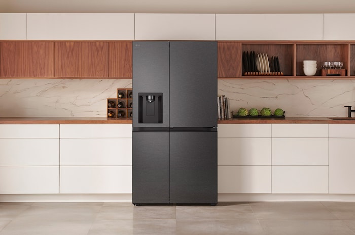 LG Side-by-Side Kühlschrank GSJC40EPPE in mattem Schwarzstahl, elegant integriert in eine moderne Küche mit weißer und hölzerner Arbeitsplatte und DoorCooling+™ Technologie.