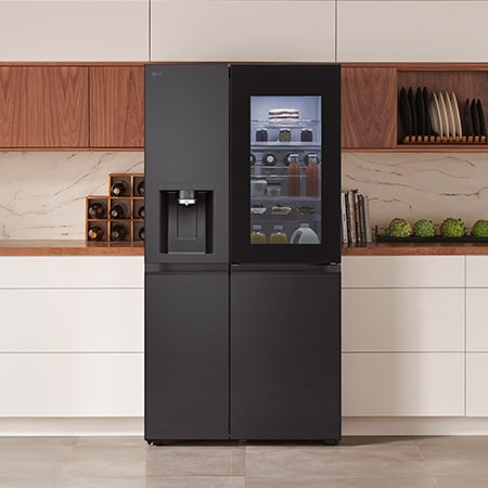 LG Side-by-Side Kühlschrank GSXB90EVDD in mattem Schwarz mit InstaView™ Door-in-Door®, integriert in eine moderne Küche mit weißen und hölzernen Schränken.