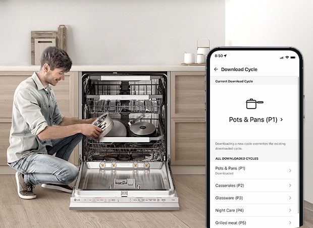 Man loading pots into an open dishwasher with a smartphone displaying a downloadable cycle for dishwashing.