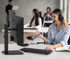 Eine Frau mit Headset arbeitet und starrt auf einen Monitor.	