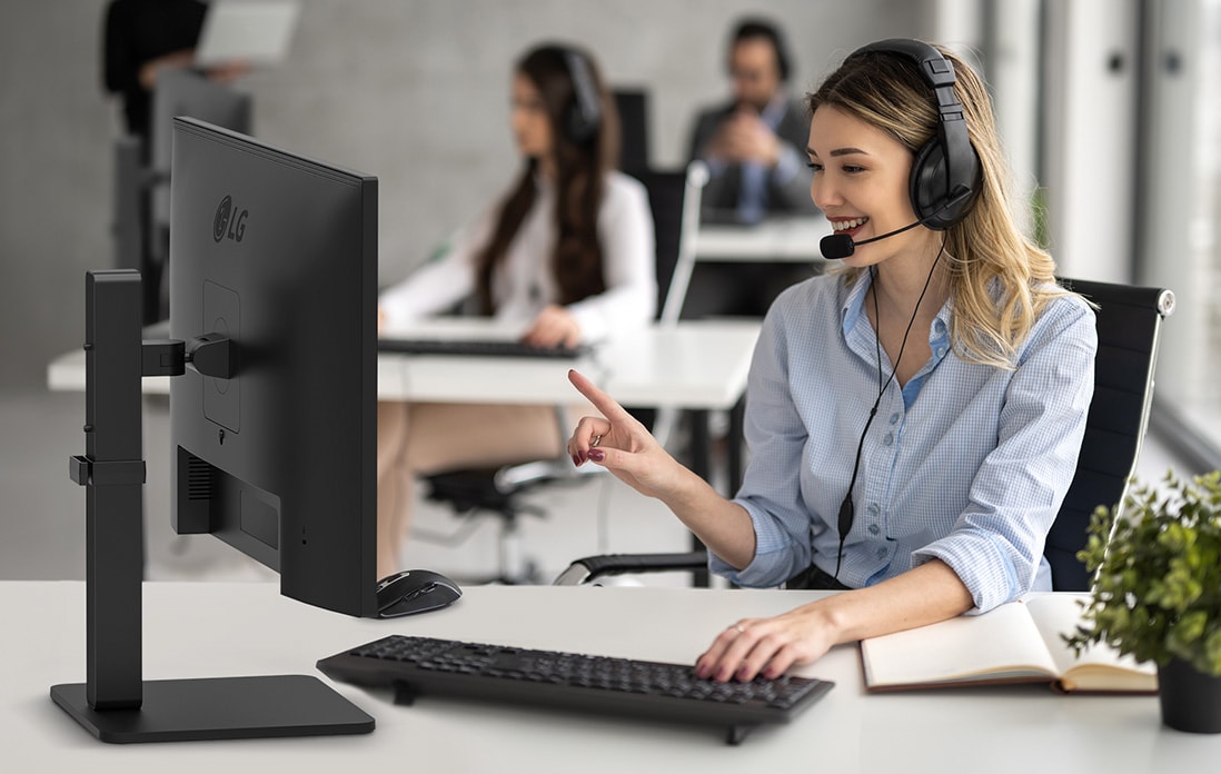 Eine Frau mit Headset arbeitet und starrt auf einen Monitor.	