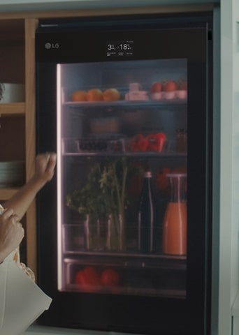 Bild einer Frau, die auf die Oberseite eines Kühlschranks klopft.