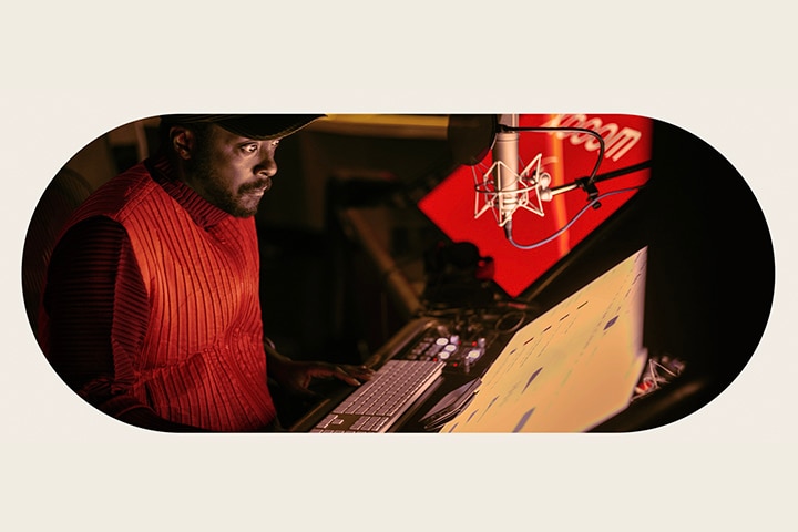 will.i.am arbeitet im Studio und schaut auf einen Bildschirm, der unter einem Mikrofon angebracht ist.