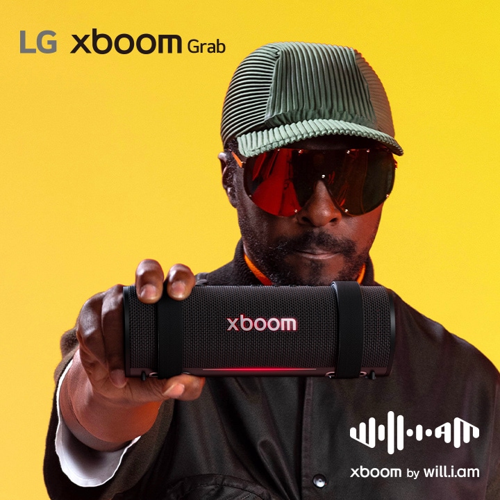 will.i.am in weißem Outfit und Sonnenbrille hält xboom Grab direkt neben sein Gesicht.