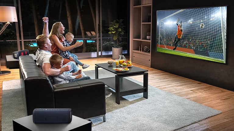 Eine Familie sitzt auf der Couch und sieht sich im Fernsehen ein Fußballspiel an.