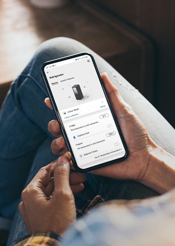 Das Bild zeigt die ThinQ-App, mit der du den Kühlschrank steuern kannst, auf einem Telefon in einer Hand.