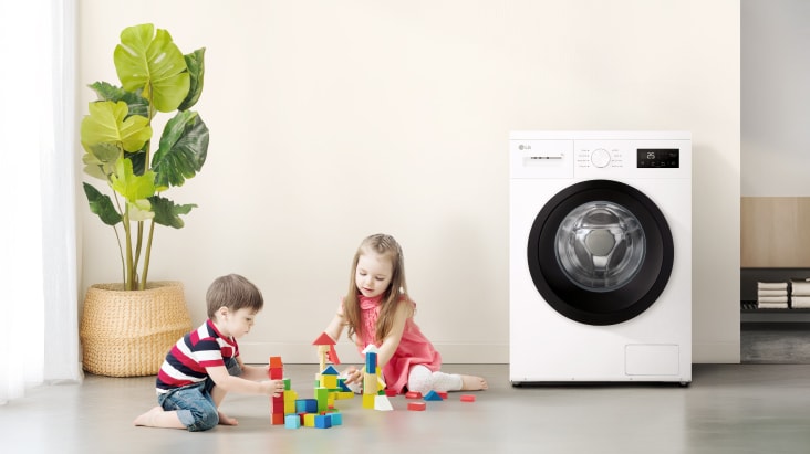 Zwei Kinder, die mit farbenfrohen Blöcken in der Nähe einer Waschmaschine spielen