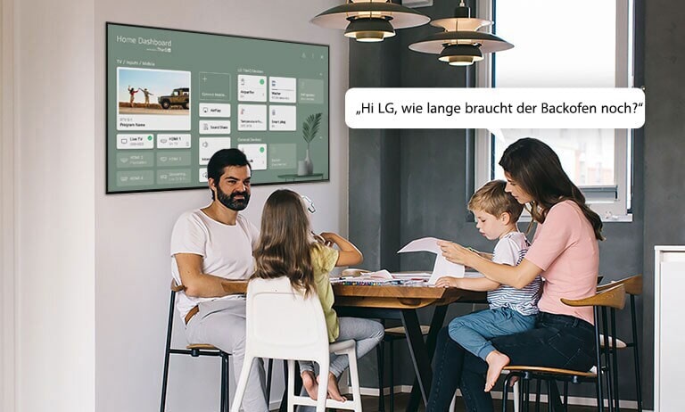 Eine Familie sitzt am Tisch und die Mutter fragt den Fernseher nach der Restzeit des Backofens.