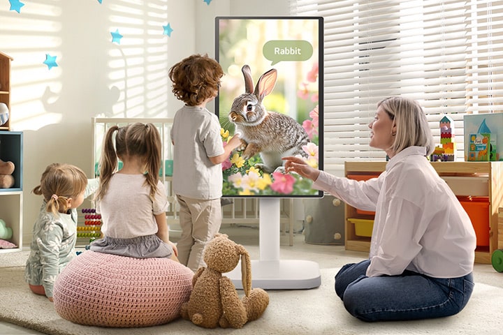 Dieses Bild zeigt eine Frau und drei Kinder, die mit einem LG Smart Monitor Swing spielen.