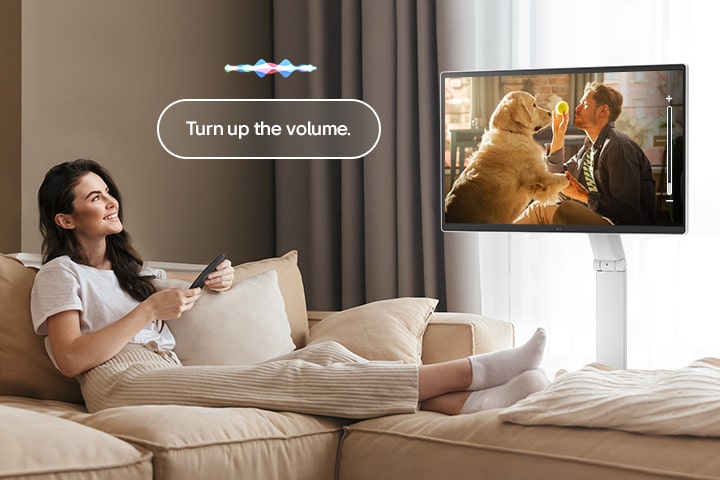 Eine Frau erhöht die Lautstärke des LG Smart Monitor Swing mit einer Magic Remote.