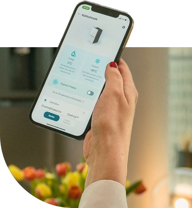 Eine Frau hält ihr Telefon mit der LG ThinQ-App in der Hand, um die Temperatur des LG InstaView Side-by-Side Kühlschrankes einzustellen.