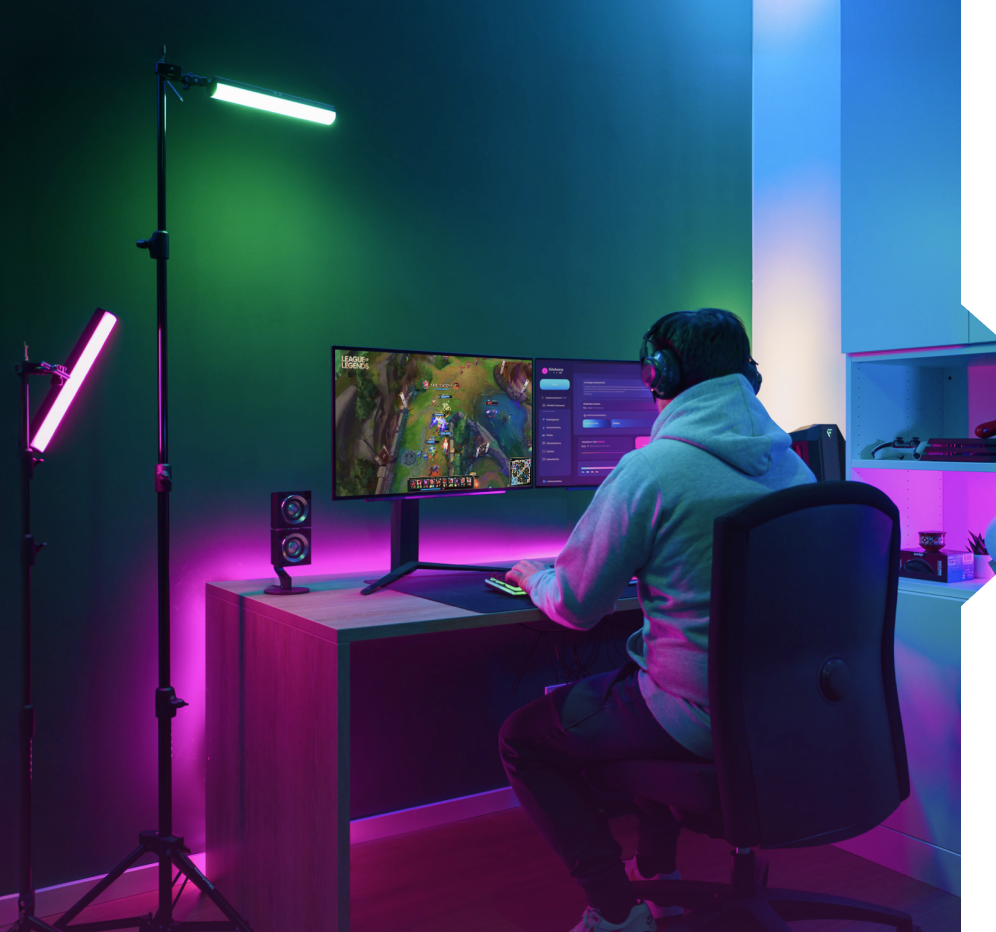 Ein Gamer in einem dunklen Raum mit LED-Lichtern und einem Dual-Monitor-Setup.