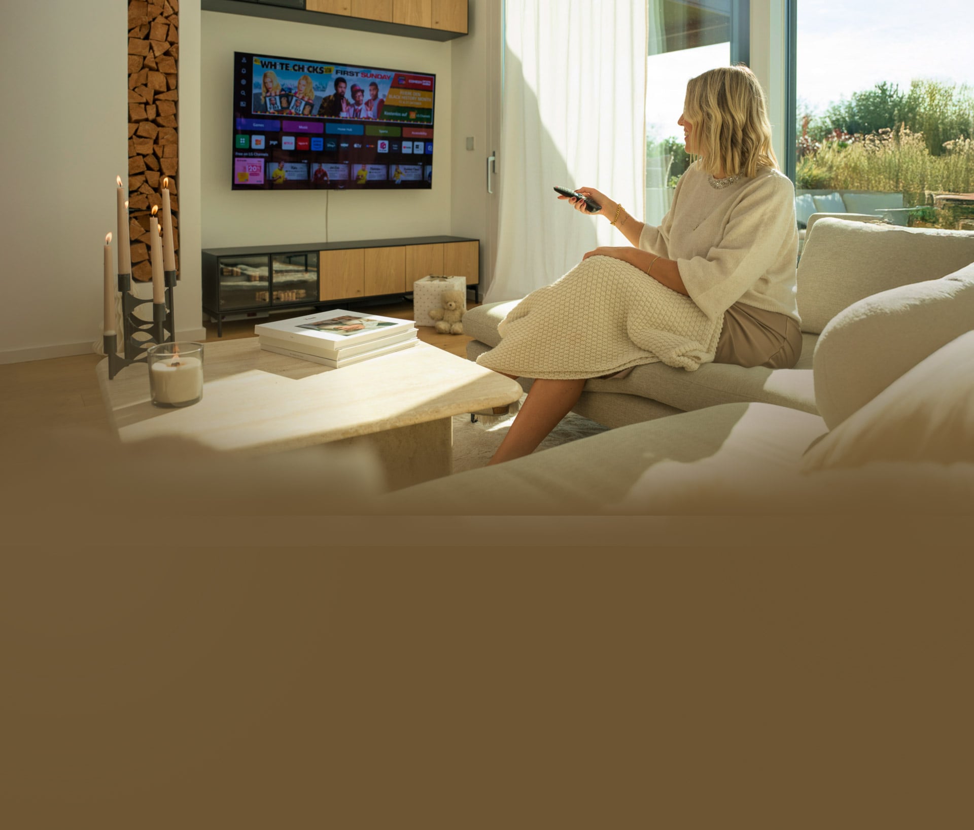 Eine Frau entspannt sich auf einem Sofa in einem modernen Wohnzimmer und benutzt eine Fernbedienung, um den LG OLED G4 4K Smart TV zu steuern.