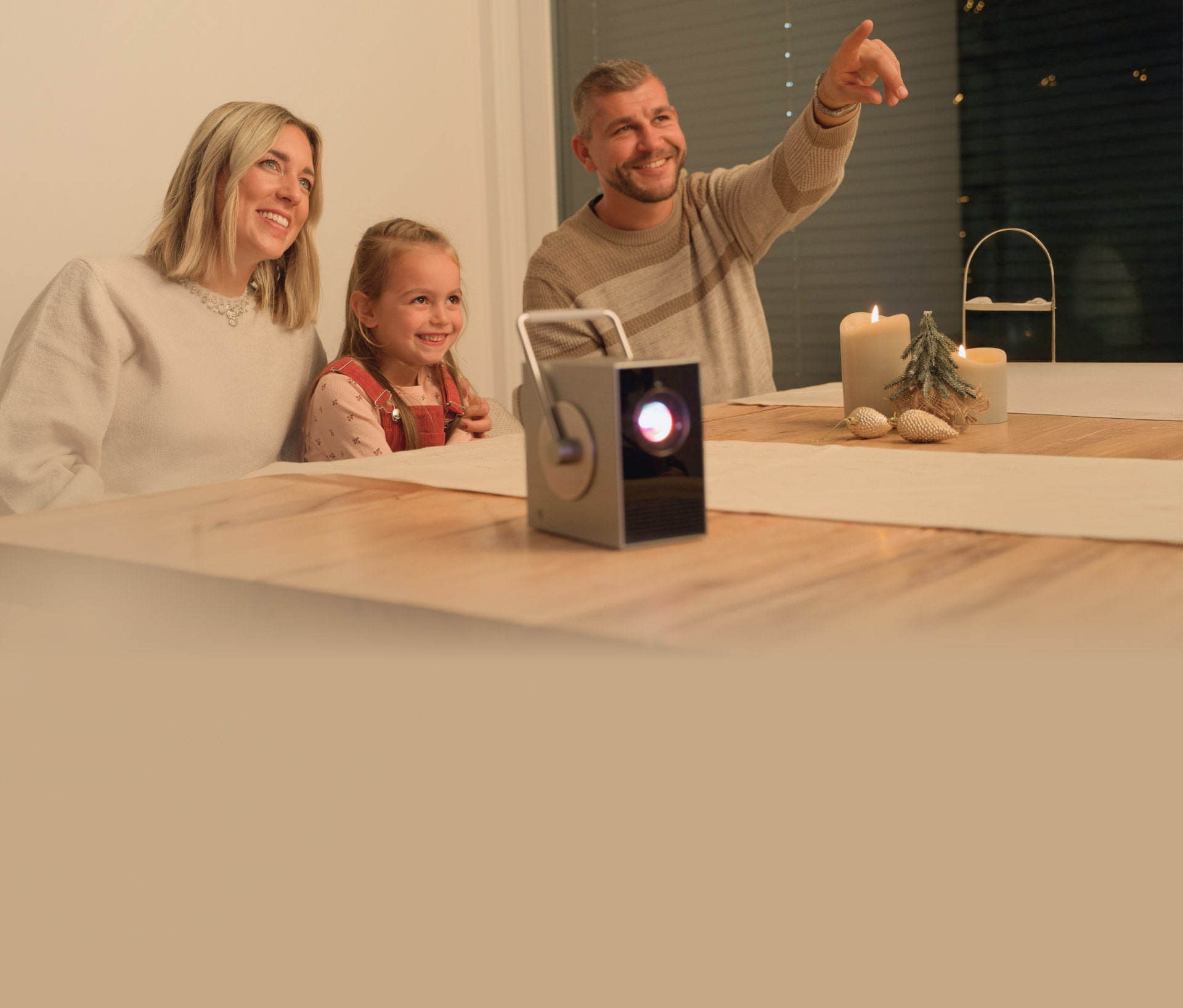 Eine Familie genießt einen gemütlichen Moment am Tisch mit dem LG CineBeam Q Tragbaren Projektor.