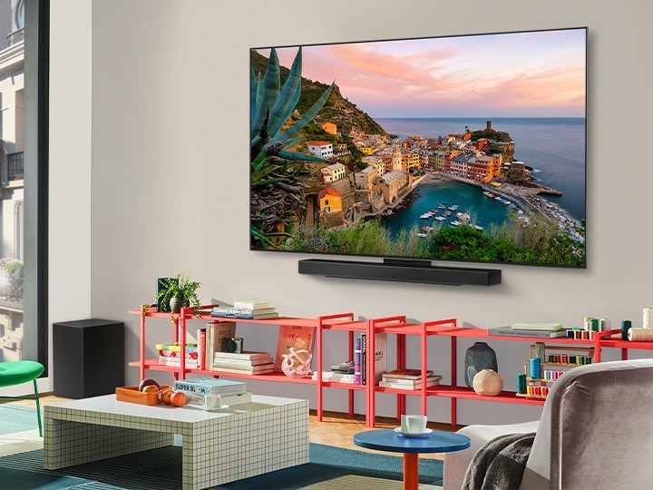 In einem farbenfrohen Wohnzimmer steht ein wandmontierter LG OLED-Fernseher mit Soundbar. Die Perspektive ist schräg und zeigt den ultraschlanken Rahmen des Fernsehers an der Wand.