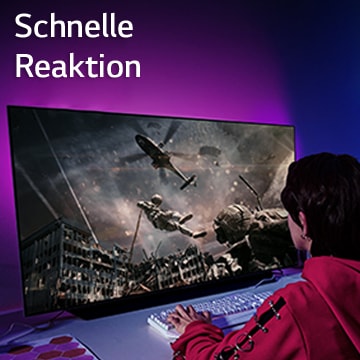Ein Mädchen spielt ein Computerspiel auf einem Großbildschirm, auf dem ein Soldat zu sehen ist, der sich aus einem Hubschrauber herunterlässt.
