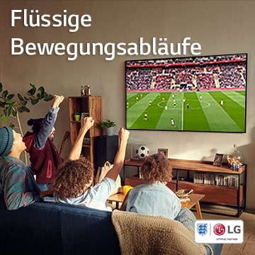 Vier Personen sitzen in einem Wohnzimmer auf einer Couch und sehen sich ein Fußballspiel an.